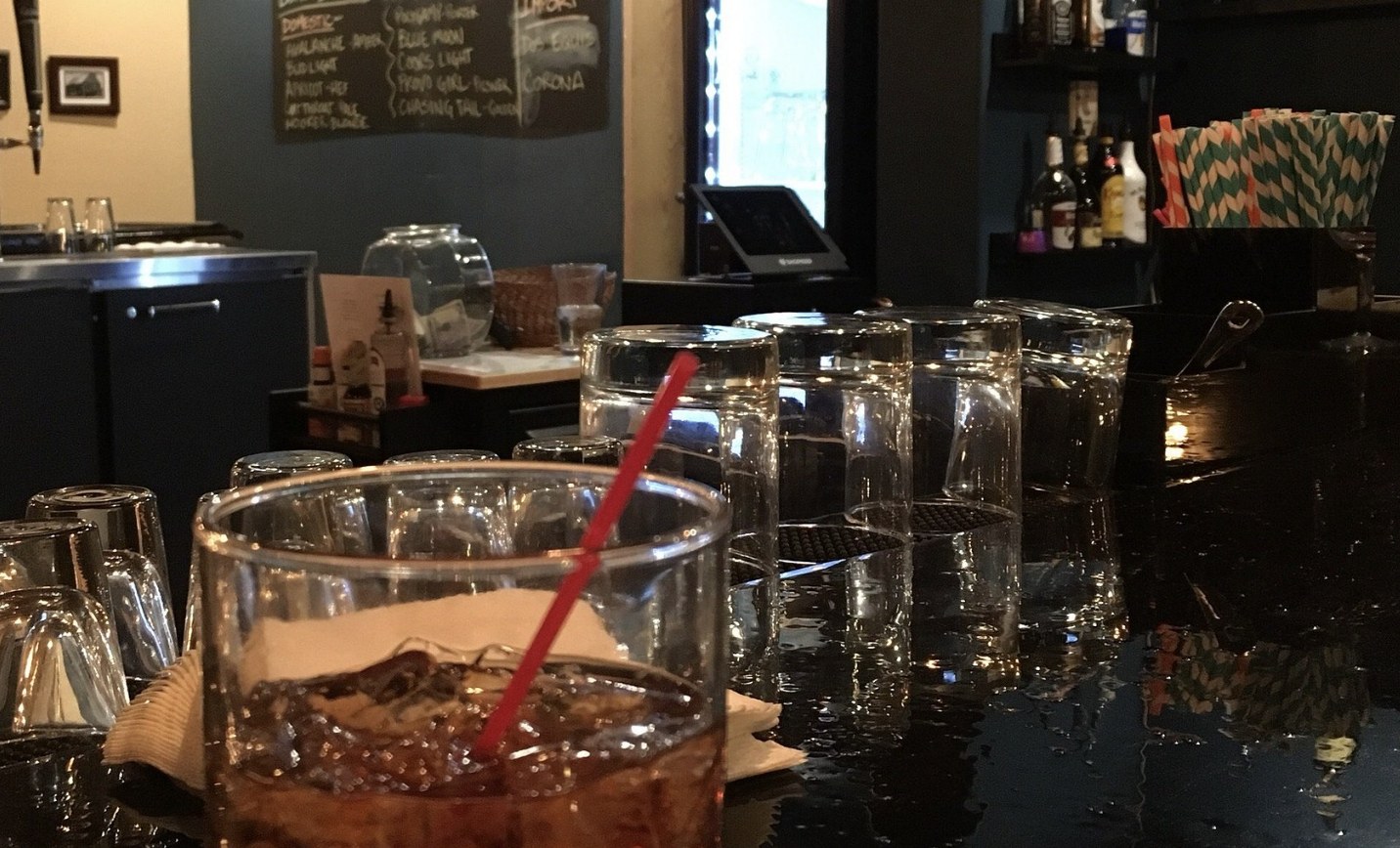 Bar counter with glassware and a chalkboard drink menu inside 4th West Pub in Escalante