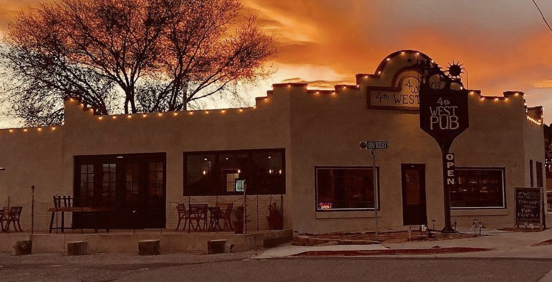 The 4th West Pub building in Escalante Utah lit up at sunset with string lights and an open sign
