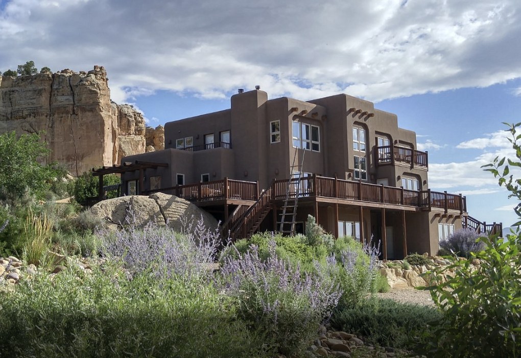 Exterior view of a southwestern style adobe home with wildflowers in the foreground near Boulder Utah