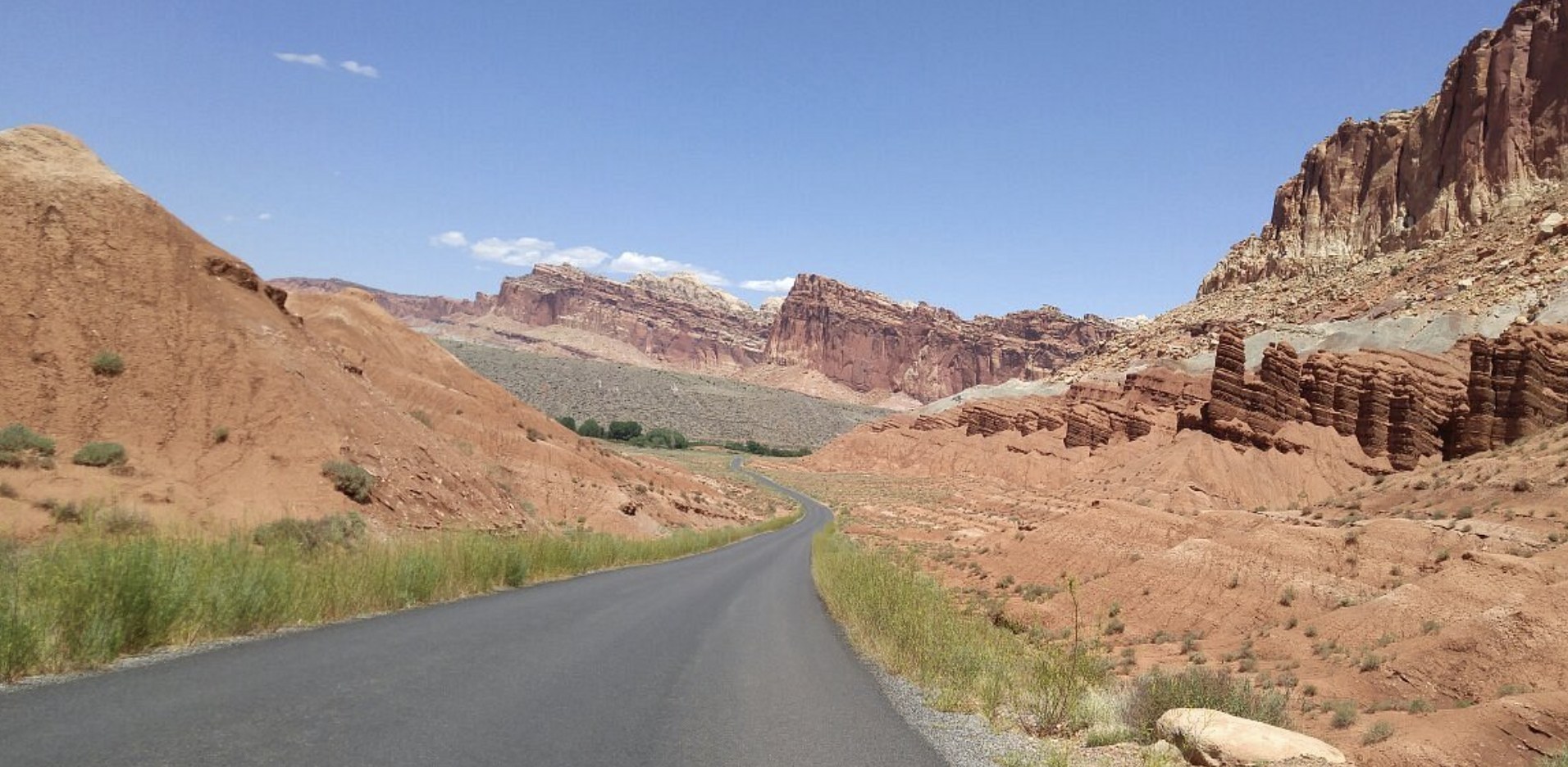 A paved road curving through a red rock canyon with tall eroded rock spires