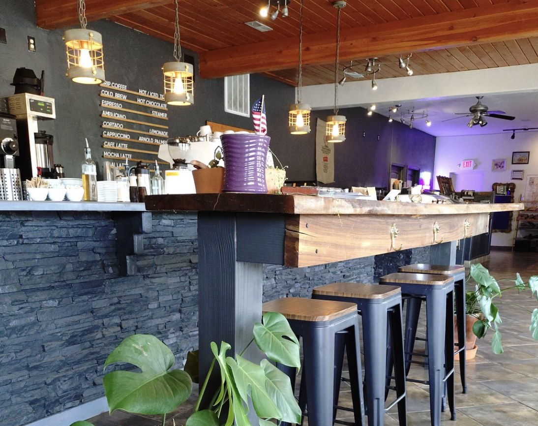 Interior of a modern coffee shop in the Escalante area with a stone bar, pendant lights, and a menu board