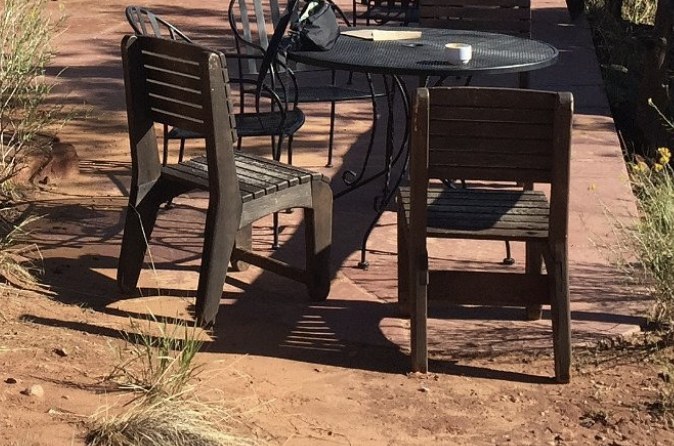 An outdoor patio with wooden chairs and a metal table at a cafe in the Escalante area