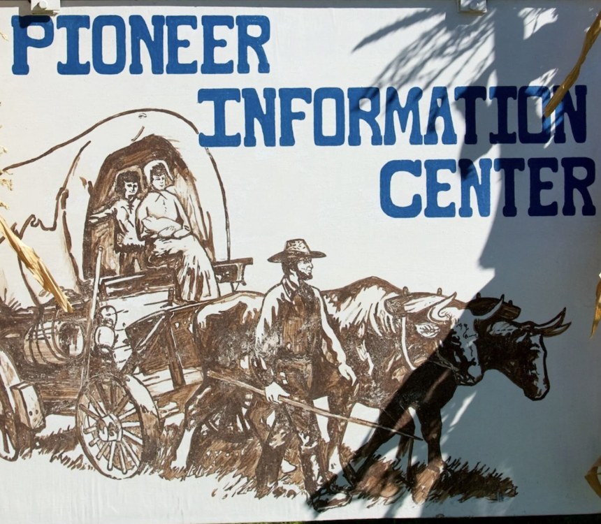 Hand painted Pioneer Information Center sign with a covered wagon illustration in Escalante Utah